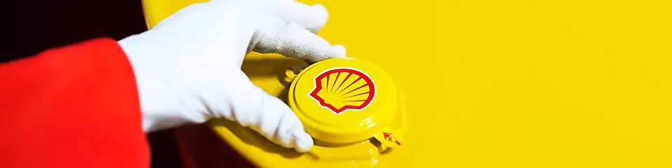 A Shell expert adjusts the lid of a barrel of lubricant displaying the Shell logo